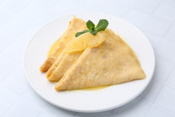 Tasty crepes Suzette on white tiled table, closeup