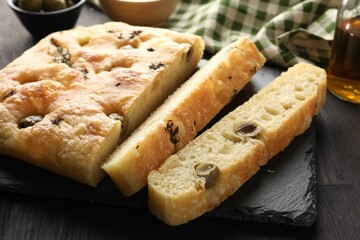 Pieces of delicious focaccia bread with olives and thyme on dark wooden table, closeup