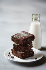 Stack of Black Bean Gluten Free Flourless  Brownies dusted with powdered sugar and plated with a glass of milk