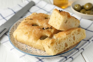 Slices of delicious focaccia bread with olives, thyme and salt on white wooden table, closeup