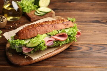 Delicious baguette sandwich with ham on wooden table