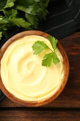 Delicious mayonnaise sauce with parsley in bowl on wooden table, top view