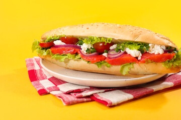 Delicious baguette with salmon on yellow background, closeup