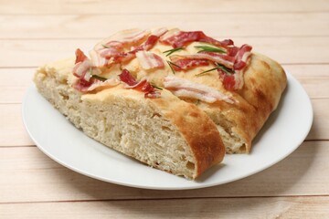 Pieces of delicious focaccia bread with bacon and rosemary on wooden table, closeup