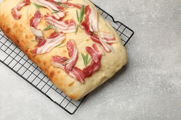 Delicious focaccia bread with bacon and rosemary on light grey table, top view. Space for text