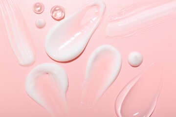 Cream and gel samples on pink background, top view