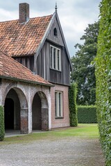 Fototapeta premium A charming historic wooden house featuring a picturesque tiled roof has been discovered nestled within a vibrant garden on a cloudy day in the serene countryside