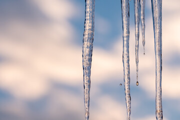 Icicles hanging against a blurred sky melting slowly