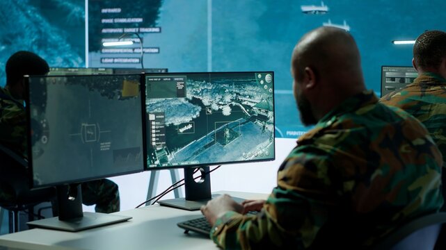 Military crew in a high tech operations command post managing information from radar cctv systems, real time data to support defense missions. Army protocols for national security. Camera A.