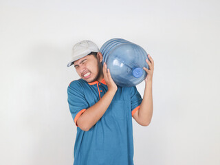 Asian delivery courier is carrying a gallon or big water bottle of mineral water with a gesture of difficulty lifting the heavy gallon