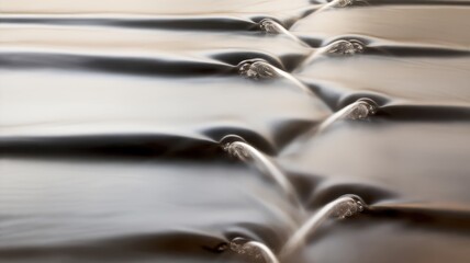 A close-up view of gentle waves creating ripples, capturing the beauty of fluid motion and soft reflections in serene water tones.