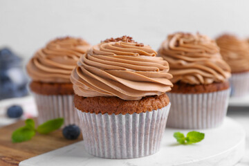 Tasty cupcakes with chocolate cream and blueberries on table, closeup