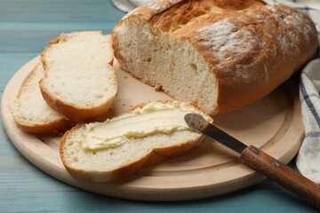 Fresh bread with butter and knife on blue wooden table, closeup
