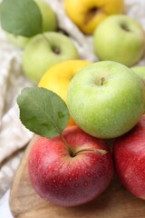 Different whole ripe apples on wooden table, closeup