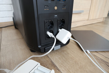 Modern portable power station, charging attached devices indoors, closeup