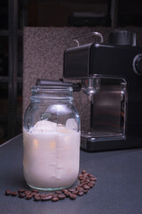 Young white-skinned Latina woman making hot drink, American-style coffee with milk and water in a coffee machine in the comfort of her home. She is happy and content.