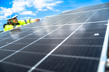 A solar technician in a high-visibility jacket and helmet stands next to a solar panel, with a...