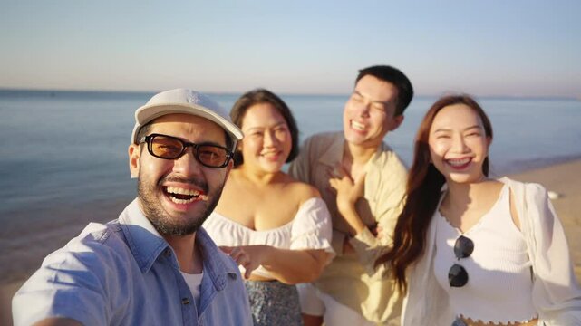 Happy man and woman using mobile phone during travel nature the sea on summer beach holiday vacation. Asian man enjoy and fun outdoor lifestyle using smartphone taking selfie with friends at the beach