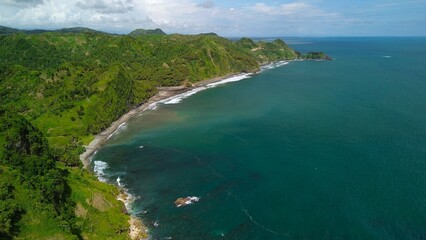 Obraz premium Aerial drone view of coastline with hills and trees, as well as view of coral cliffs and sea with waves from the ocean in Menganti Beach Kebumen Central Java Indonesia