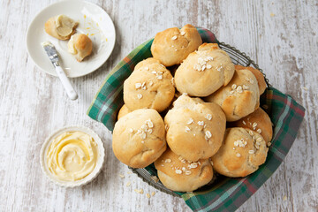 Wire basket of fresh oatmeal dinner rolls with butter
