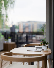 A close-up of a wooden table and armchair on a balcony of an apartment in the city.