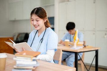 A smart and beautiful Asian female medical student in scrubs is reading or studying in the library.