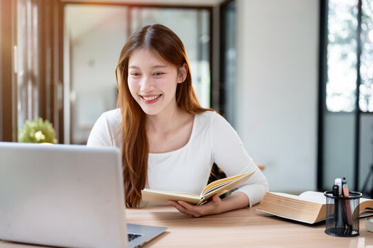 A beautiful Asian female college student working remotely from a cafe or studying in a library.
