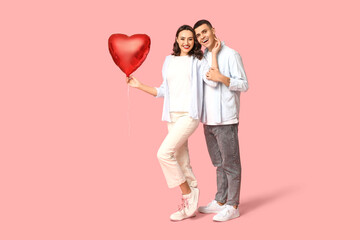 Loving young couple with heart-shaped balloon on pink background. Celebration of Saint Valentine's...