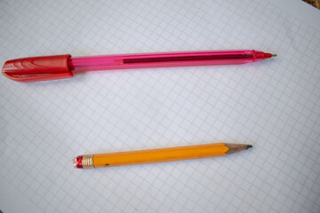 A pencil and red pen placed on a white grid paper sheet, symbolizing creativity, writing, and...