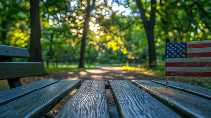 Wooden bench with American flag in a sunlit park surrounded by trees