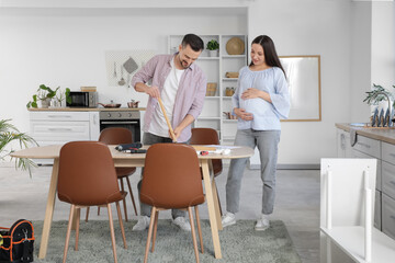 Obraz premium Happy pregnant couple assembling table in kitchen