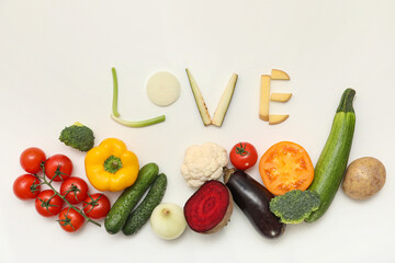 Composition with word LOVE and fresh vegetables on light background