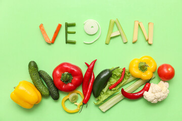 Composition with word VEGAN and different vegetables on green background