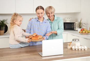 Happy family with tasty buns video chatting in kitchen