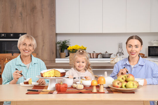 Little girl with her mom and granny eating tasty pie at table in kitchen