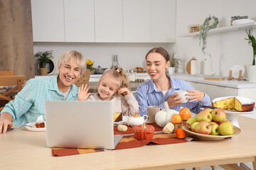 Happy family with tasty pie video chatting at table in kitchen