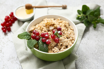 Bowl with tasty oatmeal and cranberries on grey grunge background, closeup