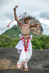 SIGIRIYA, SRI LANKA - JULY 16, 2024 : A Ves Dancer, also known as a Kandyan Dancer or Up Country Dancer performs at Sigiriya in Sri Lanka. In the background stands Sigiriya Rock.