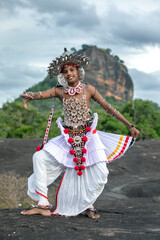 SIGIRIYA, SRI LANKA - JULY 16, 2024 : A Ves Dancer, also known as a Kandyan Dancer or Up Country Dancer performs at Sigiriya in Sri Lanka. In the background stands Sigiriya Rock.