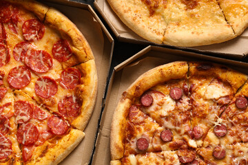 Cardboard boxes with tasty pizza on black grunge background, closeup