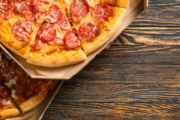Cardboard boxes with tasty pizza on wooden background