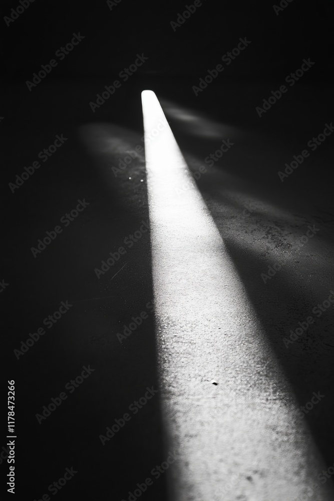 Poster a striking black and white image showcasing a single beam of light illuminating a dark floor, creati