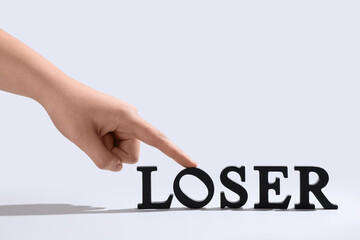 Female hand and word LOSER on white background