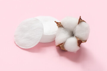 Cosmetic pads and cotton flower on pink background