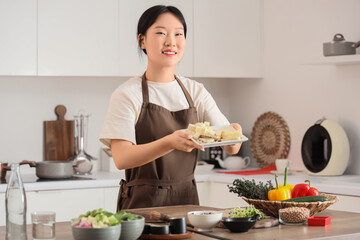 Young Asian woman with tasty tofu in kitchen