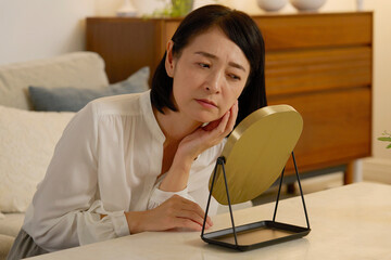 肌トラブルに悩む50代の女性　夜のリビング