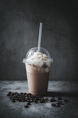 Iced coffee latte in a plastic takeaway cup isolated on a gray background