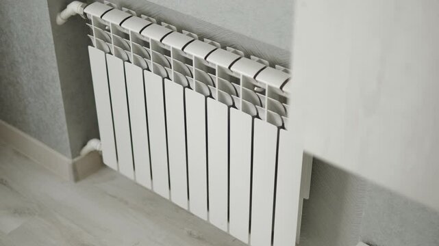 Aluminum modern and energy efficient white heating radiator on wall of room. Background of centralized heating system and multi section convector.