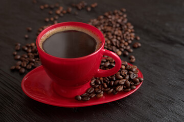 Cup of coffee on a saucer on a black background for breakfast