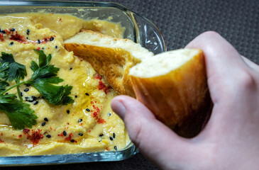 Close-up of a child's hand dipping a piece of flatbread into homemade hummus placed in a glass...